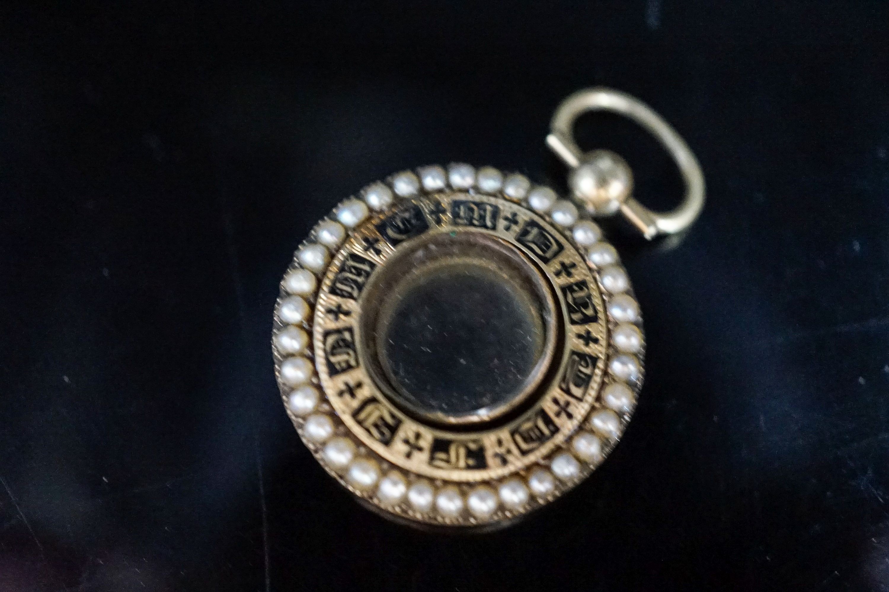 A William IV yellow metal, black enamel and split pearl mounted glazed circular mourning pendant vacant enamelled mourning brooch, 25mm. with engraved inscription, gross 6.5 grams.